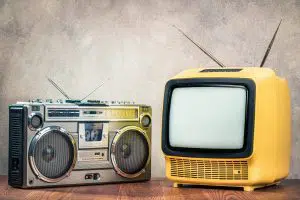Old portoable TV and radio sitting next to each other on a wooden table - GAINSWave